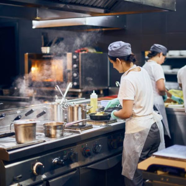 the team of cooks backs in the work in the modern kitchen, the workflow of the restaurant in the kitchen. Copy space for text.